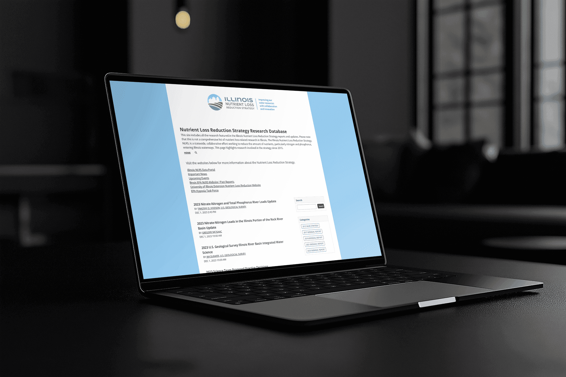 A laptop displaying the NLRS Research Database website, highlighting research from Illinois Nutrient Loss Reduction Strategy reports and updates.